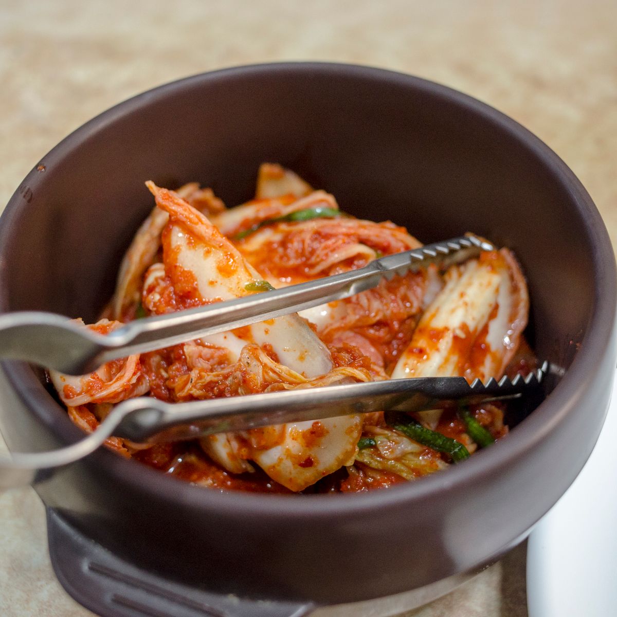 검은 도기 그릇에 담긴 김치와 집게
